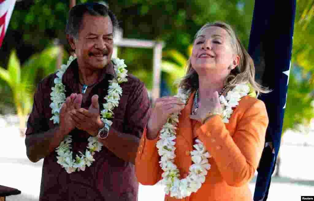 Clinton adjusts her black pearl necklace, a gift from Cook Islands' Prime Minister Henry Puna (L) during a sustainable development and conservation event in Rarotonga, August 31, 2012. 