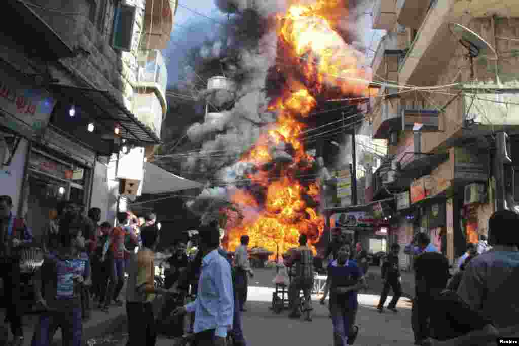 Residents run from a fire at a gasoline and oil shop in Aleppo's Bustan Al-Qasr neighborhood. Witnesses said the fire was caused by a bullet fired by a sniper loyal to Syrian President Bashar al-Assad at the Karaj al-Hajez crossing, Oct. 20, 2013.