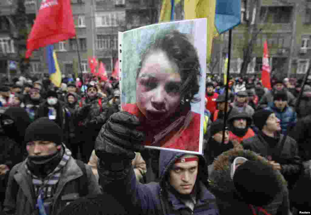 A protester holds a picture of journalist Tetyana Chornovil, who was beaten and left in a ditch just hours after publishing an article on the assets of top government officials, during a protest rally in front of the Ukrainian Ministry of Internal Affairs in Kyiv.