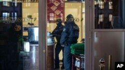 Masked police stand in an ice parlor in Duisburg, western Germany, Wednesday, Dec. 5, 2018 as authorities conduct coordinated raids in Germany, Italy, Belgium and the Netherlands in a crackdown on the Italian mafia.