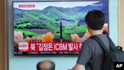 在首尔火车站，旅客观看关于朝鲜发射导弹的电视新闻（2017年7月4日）