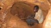 FILE - A man sits in a hole he dug in the rock with makeshif tools in search for gold at the Soedoumbofor site near the eastern Cameroonian town of Batouri, June 1, 2008.