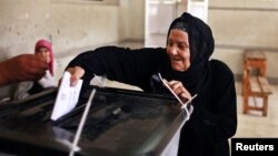 Seorang wanita memasukkan surat suaranya ke dalam kotak suara pemilu presiden Mesir yang bersejarah di sebuah TPS di Kairo (24/5). 