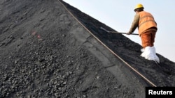 一名中国工人在山东日照港挥铲整理从澳大利亚进口的煤炭。（资料照片）