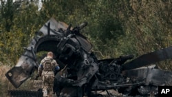 A Ukrainian soldier passes by a Russian tank damaged in a battle in a just freed territory on the road to Balakleya in the Kharkiv region, Ukraine, Sunday, Sept. 11, 2022. (AP Photo)