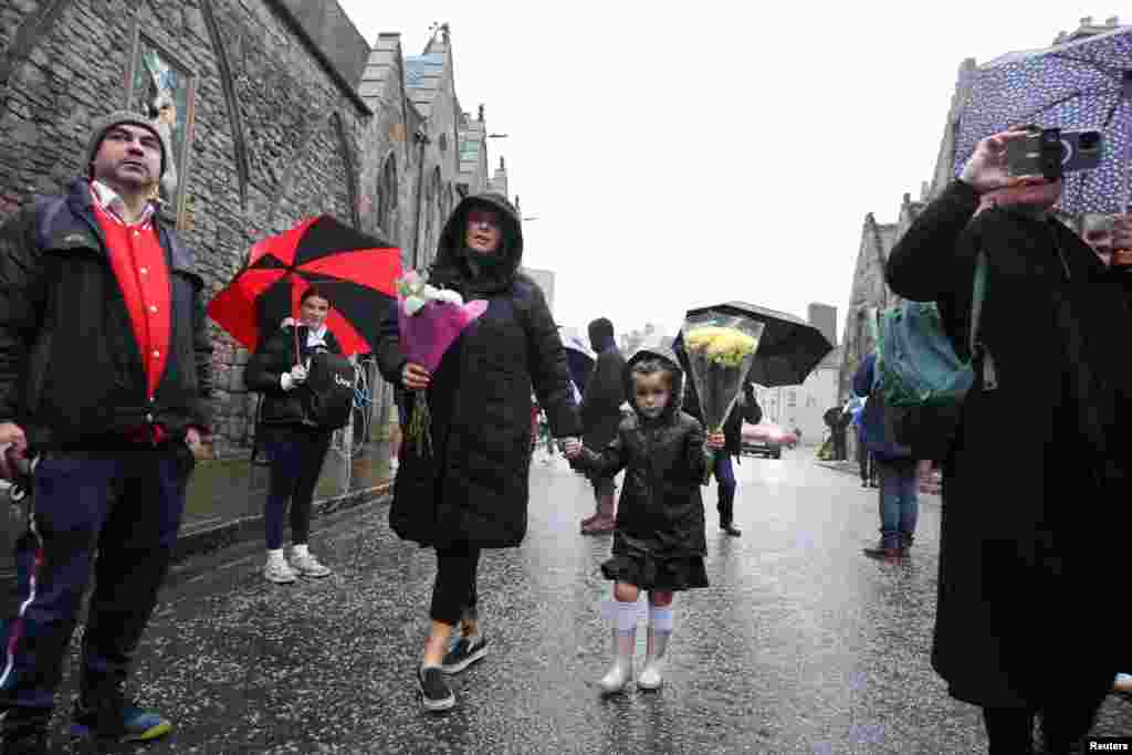 People carry flowers near the Palace of Holyroodhouse, after the announcement Queen Elizabeth&#39;s death, Sept. 8, 2022.