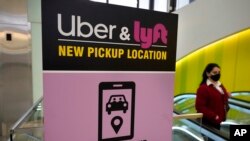 Seseorang berjalan kaki melewati papan petunjuk arah ke area penjemputan Uber dan Lyft di Bandara Internasional Logan, Boston, 9 Februari 2021. (Foto: AP)
