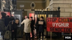 一群香港示威者在伦敦抗议香港经济质易办事处农历新年酒会，网名“揽炒巴"的香港民主派人士刘祖迪(图中手持抗议纸牌)2月13日傍晚带领示威者在市中心国宴厅外示威 (美国之音/郑乐捷)