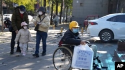 北京一家儿童医院外一名坐在轮椅上的男孩手拿医院影像科的片子。（2023年11月24日）