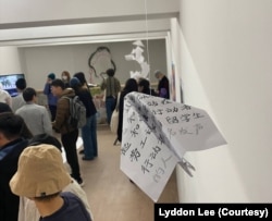 伦敦“白纸周年”艺术展上观众观看作品。（美国之音 李伯安）