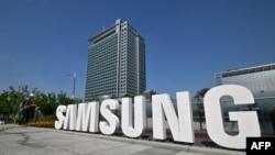 Seorang pekerja menyirami taman bunga di sebelah logo Samsung Electronics di kantor pusat perusahaan di Suwon, 13 Juni 2023.