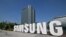 Seorang pekerja menyirami taman bunga di sebelah logo Samsung Electronics di kantor pusat perusahaan di Suwon, 13 Juni 2023.
