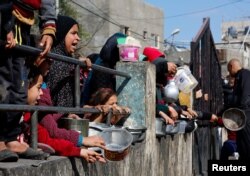 Palestinian children wait to receive food cooked by a charity kitchen amid shortages of food supplies, as the ongoing conflict between Israel and the Palestinian Islamist group Hamas continues, in Rafah, in the southern Gaza Strip, Feb. 20, 2024.