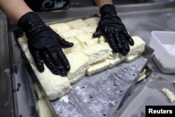 A worker prepares halloumi on Pantelis Panteli's farm in Kokkinotrimithia, Cyprus February 10, 2024. (REUTERS/Yiannis Kourtoglou)