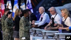 Presiden AS Joe Biden, koki Robert Irvine, dan ibu negara Jill Biden membantu menyajikan makanan Thanksgiving kepada anggota pasukan militer AS dan keluarganya di Norfolk Naval Station di Norfolk, Virginia, pada 19 November 2023. (Foto: AP/Manuel Balce Ceneta)