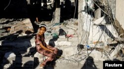 一名巴勒斯坦小姑娘坐在加沙地带南部法拉市被以色列炸毁的房屋前。（2024年4月17日）