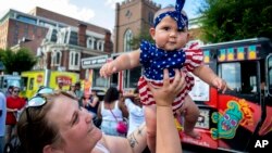 ນາງ Amber Hess, ຍົກລູກສາວນ້ອຍ ນາງ Emorie Narvaez ຂຶ້ນ ໃນລະຫວ່າງງານບຸນລົດອາຫານ ຂອວັນທີ 4 ກໍລະກົດ ໃນເມືອງ Harrisburg ຢູ່ຕໍ່ໜ້າສວນສາທາລະນະ River Front Park ໃນເມືອງ Harrisburg, ລັດເພັນຊິລວາເນຍ, ວັນທີ 4 ກໍລະກົດ 2023.