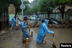 北京居民开始清理被洪水淹没的街道。（2023年8月1日）