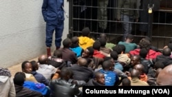 Arrested opposition members are told to sit on a cold floor surrounded by police guards at the Harare Magistrates Court in Zimbabwe, June 18, 2024.