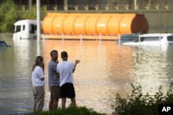 People look out at floodwater covering a major road in Dubai, United Arab Emirates, Wednesday, April 17, 2024. (AP Photo/Jon Gambrell)