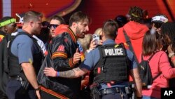 Lapolis eskote jwe Kansas City Noah Gray ak ko ekipye li yo pou ede yo soti sou sen nan apre yon fiziyad pandan parad viktwa yo a nan Kansas City, eta Missouri, 14 Fevriye 2024. 