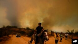 A resident flees an encroaching forest fire in Vina del Mar, Chile, Feb. 3, 2024. 