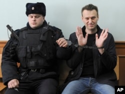 FILE - Russian opposition leader Alexei Navalny, right, poses for press as he sits handcuffed in court in Moscow, Russia on March 30, 2017. (AP Photo, File)