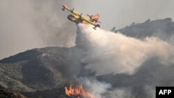 একটি অগ্নিনির্বাপক বিমান ২০২৩ সালের ২৫ জুলাই রাজধানী শহর থেকে প্রায় ৭০ কিলোমিটার দক্ষিণ-পশ্চিমে রোডসের দক্ষিণ অংশে ভাটি গ্রামের কাছে দাবানলের ওপর পানি ফেলছে।