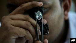 FILE - A man looks at a polished lab-grown diamond at Greenlab Diamonds, in Surat, India, Monday, Feb. 5, 2024. Diamonds, whether lab grown or natural, are chemically identical and entirely made out of carbon. (AP Photo/Ajit Solanki)