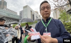 将军澳反填海游行纠察、中科监察主席潘焯鸿展示向游行人士派发的挂颈号码牌 (美国之音/汤惠芸)