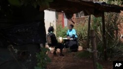 Siridzayi Dzukwa, right, talks to Tambudzai Tembo outside her house near Harare, Zimbabwe, May 15, 2024. In Zimbabwe, talk therapy involving park benches and a network of grandmothers has become a saving grace for people with mental health issues.