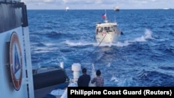 一艘菲律宾‘海岸警卫队船只拖着一艘遭中国海岸警卫队水炮攻击毁坏了的菲律宾供应船驶向有争议的第二托马斯岛礁（中国称为仁爱礁）。（2023年12月10日）