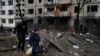 People walk past a damaged residential building following a missile strike in Kyiv on Dec. 13, 2023, amid Russian invasion of Ukraine.
