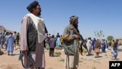Taliban security personnel stand guard as Afghans mourn at a burial ceremony of the slain Shiite Muslims after gunmen attacked a mosque in Guzara district of Herat province on April 30, 2024.