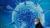 一名男子走过英国一家研究生物病毒的科研中心外的广告墙。（2020年8月3日）