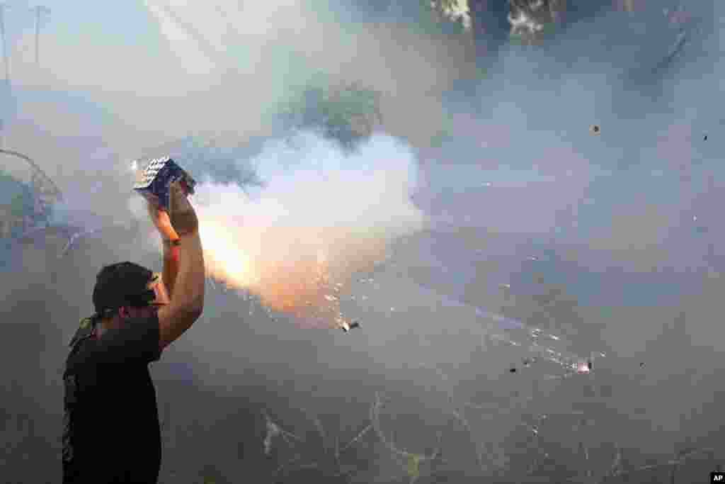A protester launches fireworks at riot police during a demonstration, in solidarity with the Palestinian people in Gaza, near the U.S. embassy in Aukar, a northern suburb of Beirut, Lebanon. (AP Photo/Bilal Hussein)