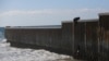 A migrant climbs the border fence to cross into the US to request asylum, at Playas de Tijuana, in Tijuana, Mexico, Oct. 2, 2023. 