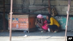 FILE - Women take cover during a gun battle between police and gang members in Port-au-Prince, Haiti, Friday, March 1, 2024. (AP Photo/Odelyn Joseph)