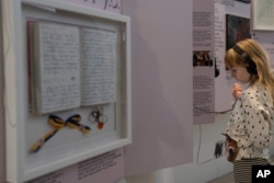 A child listens to audio with a video at the War Diaries exhibition, showcasing the personal diaries of Ukrainian children who have witnessed the war, hosted by the Amsterdam city hall , Netherlands, Thursday, Aug. 17, 2023. (AP Photo/Peter Dejong)