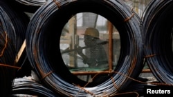 资料照片: 2009年7月9日山西省长治市一名工人走过建筑工地的钢丝卷