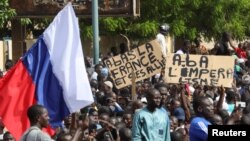 示威人士在尼日尔首都尼亚美举起一面俄罗斯旗帜进行反法和支持政变的游行。（2023年7月30日）