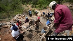 Members of Kyemoo Power, a self-help group, construct a sand dam in Makueni County, Kenya on Thursday, Feb. 29, 2024. Building sand dams helps minimize water loss through evaporation and recharges groundwater. (AP Photo/Brian Inganga)