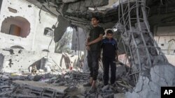 রাফায় রাতভর ইসরায়েলি হামলার পর ফিলিস্তিনিরা একটি বাড়ির ধ্বংসস্তূপে দাঁড়িয়ে আছে। ৩ মে, ২০২৪।