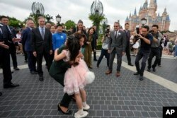 美国商务部长吉娜·雷蒙多在参观上海迪斯尼乐园期间拥抱一个身穿玲娜贝儿服装的中国小女孩。（2023年8月30日）