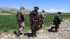 FILE - Armed Taliban security personnel walk along a wheat field in Argo district, Badakhshan province, on May 6, 2024. 