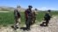 FILE - Armed Taliban security personnel walk along a wheat field in Argo district, Badakhshan province, on May 6, 2024. 