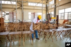 Taga Nuwagaba, a bamboo farmer and businessman who owns a bamboo furniture factory, holds a piece of furniture in Wakiso, Uganda on March 13, 2024. (AP Photo/Dipak Moses)