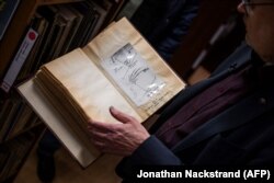 Arsiparis Clas Svahn melihat sebuah buku di Archives for the Unexplained (AFU) di Norrkoping, Swedia pada 12 Maret 2024. (Foto: Jonathan Nackstrand/AFP)