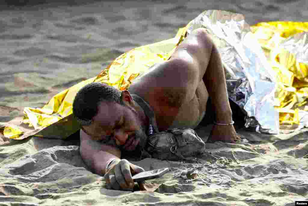 A migrant rests on the sand after arriving in a fiber boat at Las Burras beach in San Agustin, on the island of Gran Canaria, Spain, July 19, 2024.