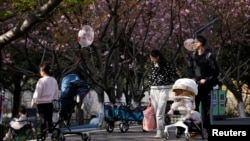 上海一个公园里父母推着婴儿车赏春。（2023年4月2日）